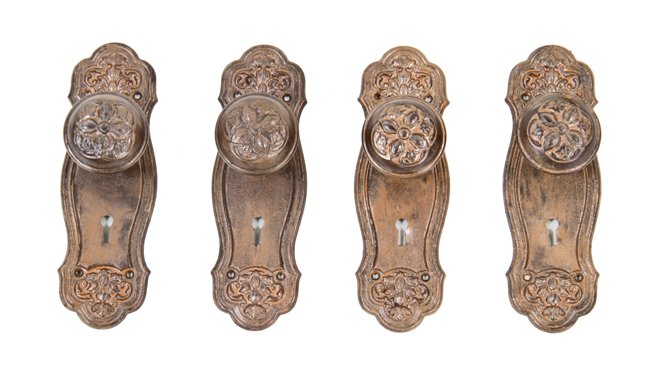 group of four matching early 20th century american  wrought ornamental steel interior residential doorknobs with matching backplates