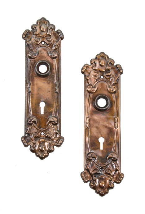 pair of c. 1910 american interior residential stamped wrought steel "alba" pattern doorknob backplates with cartouche and leafage