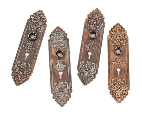 two matching early 20th century ornamental cast iron copper-plated interior residential doorknob escutcheons with wrought steel thimbles