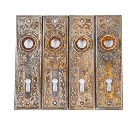 group of four matching early 1900's american interior residential stamped or pressed steel passage door backplate with floral motifs