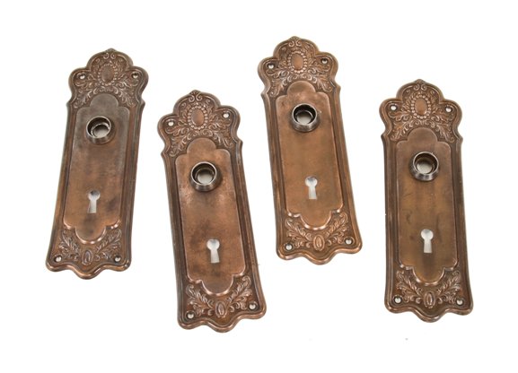 group of four matching c. 1910-20 interior residential stamped ornamental steel backplates with copper-plated finish