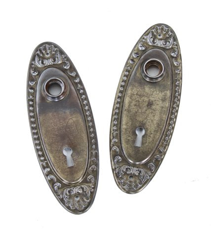 pair of early 20th century american antique stamped ornamental steel oval-shaped passage door backplates or escutcheons