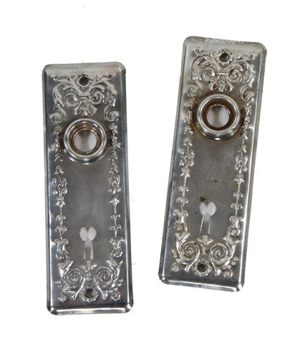two matching early 20th century nickel-plated ornamental stamped wrought steel interior residential doorknob backplates with protruding collars