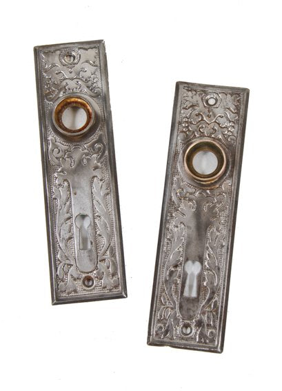 two matching early 20th century american ornamental stamped steel interior residential doorknob backplates with single keyholes
