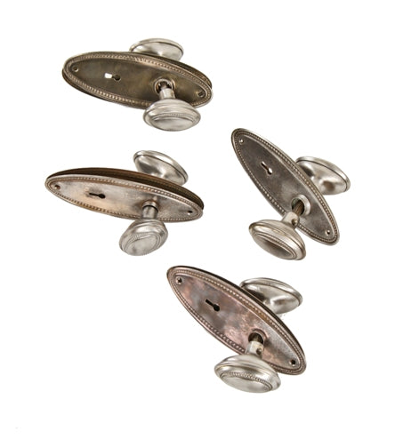 group of four matching original early 20th century ornamental stamped steel interior residential passage door locksets with beaded borders