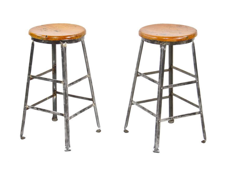 matching pair of c. 1930's american industrial refinished riveted heavy gauge steel four-legged factory workshop stools with intact maple wood seats