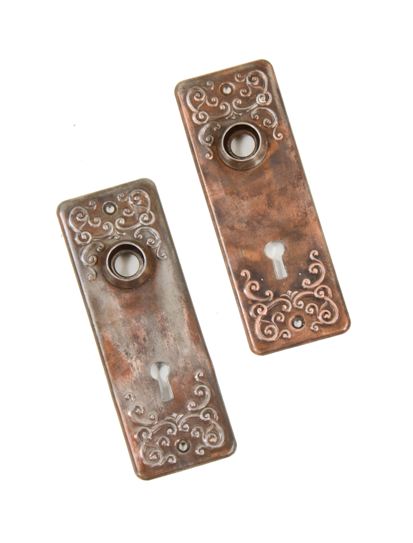 matching set of original early 20th century interior residential ornamental stamped steel doorknob backplates with partially intact copper-plated finish