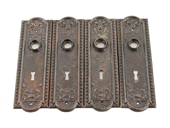 group of four matching original early 20th century american antique stamped steel "como" pattern doorknob backplates