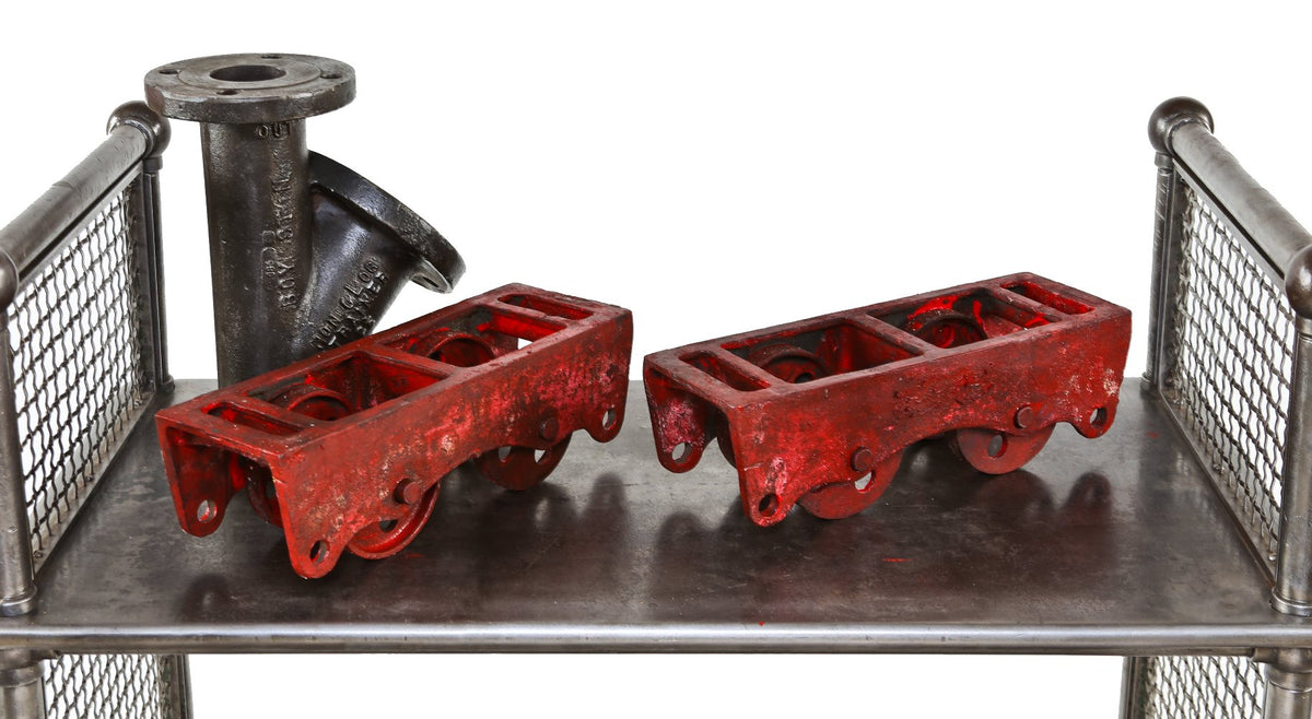 two matching late 19th or early 20th century heavy duty painted red cast iron tool chest trucks with eight perforated wheels or casters