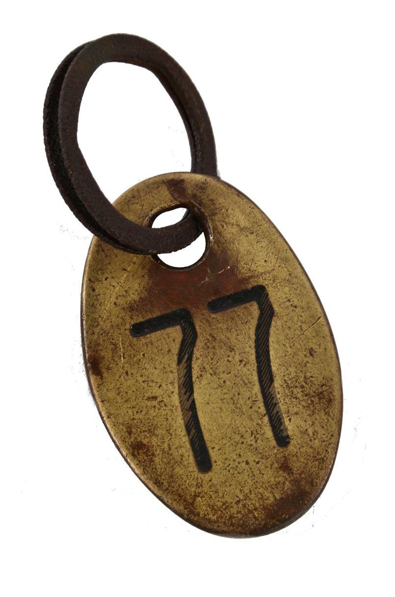heavy cast brass double-sided weathered and worn cow ear tag with lightly incised numbers and steel ring