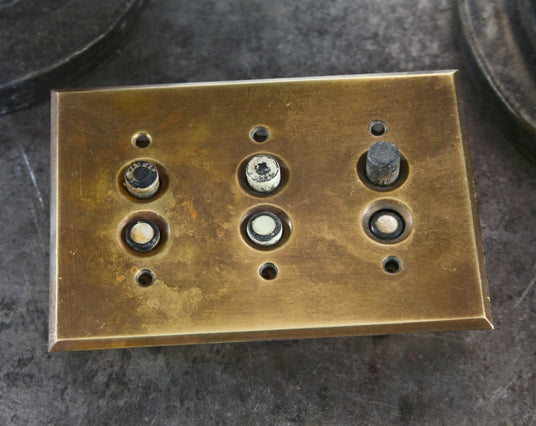 completely intact early 20th century three-gang horizontal interior residential push button wall switch with heavily machined brass backplate
