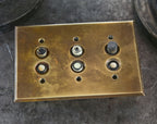 completely intact early 20th century three-gang horizontal interior residential push button wall switch with heavily machined brass backplate