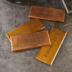 four original turn of the century american industrial beveled edge copper "equalizer" switchboard identification plaques with black enameled inlay