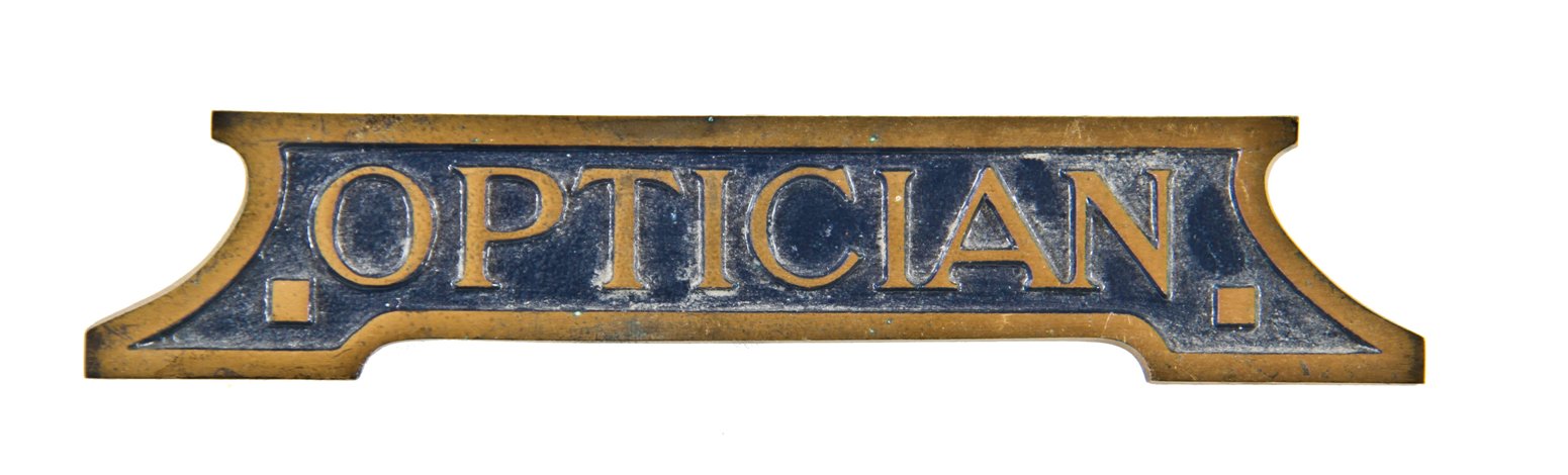 rare early 20th century single-sided diminutive ornamental cast brass optician's office desk plaque with blue enameled inlay