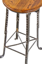 all original and well-maintained fully adjustable c. 1920's antique american industrial four-legged angled steel factory machinist stool with oak wood seat and backrest