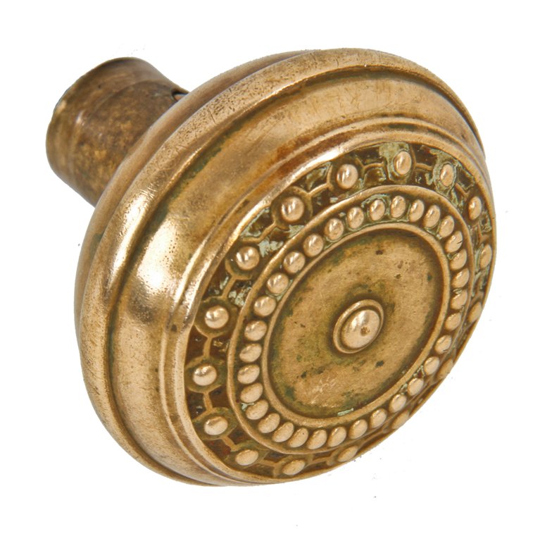 single early 20th century wrought ornamental brass "como" pattern antique american banded rim passage size doorknob with a mostly uniform finish