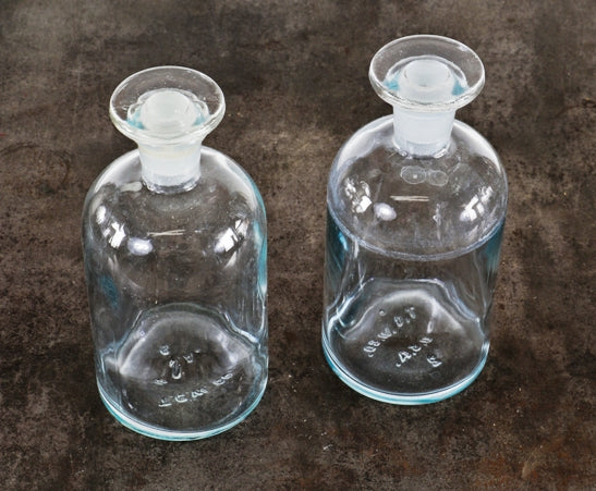 two matching american industrial reinforced clear glass research laboratory reagent bottles with intact ground glass disc-shaped stoppers