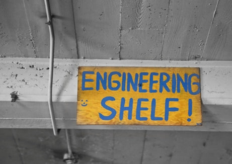 original and brightly colored hand-painted american industrial folk art single-sided "engineering shelf" wood sign with bold blue lettering against a yellow background