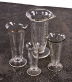 assortment of original early 20th century antique american medical wheel-cut etched glass fanciful pharmaceutical conical-shaped glass measures with pedestal bases
