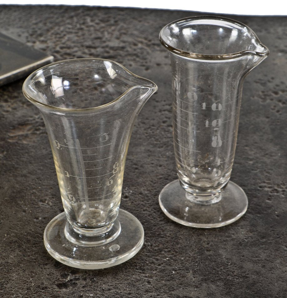 set of two all original and intact american antique lightly etched heavy clear glass drugstore apothecary measures with weighted round bases