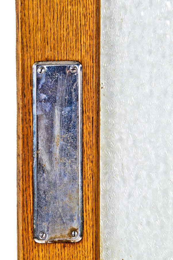 one of two matching original original early 20th century varnished golden oak wood residential pantry swinging door with intact large "florentine" pattern privacy glass pane