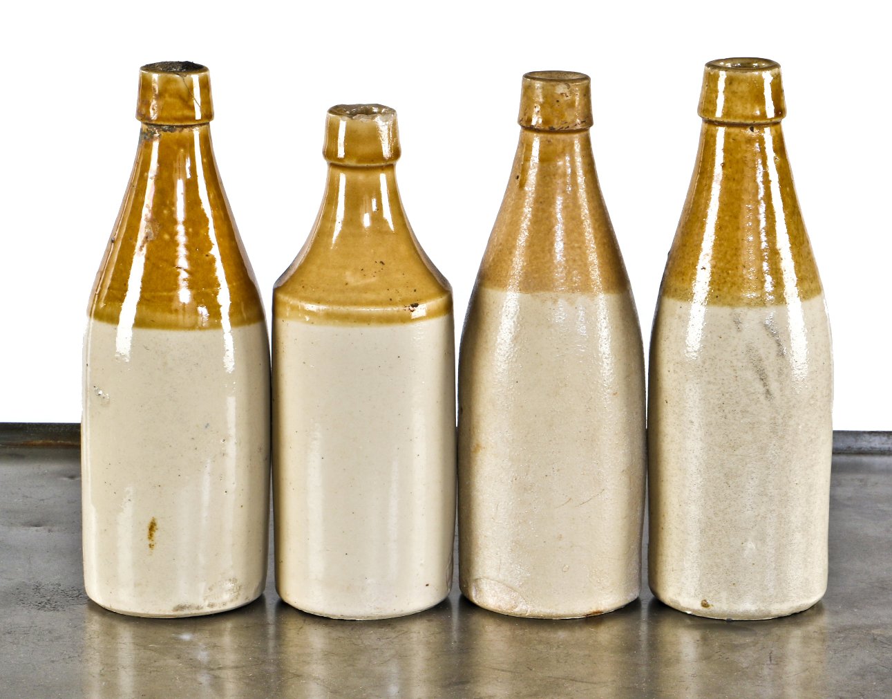 hard to find lot of four nearly identical privy dug mid-nineteenth century imported salt glazed two tone stoneware ale bottles manufactured by various scottish pottery makers.