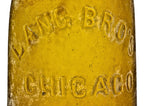 exceptionally rare antique american mid-nineteenth century privy dug vibrant yellow colored champagne style beer bottle with applied ring fabricated for the chicago bottlers the lang brothers.