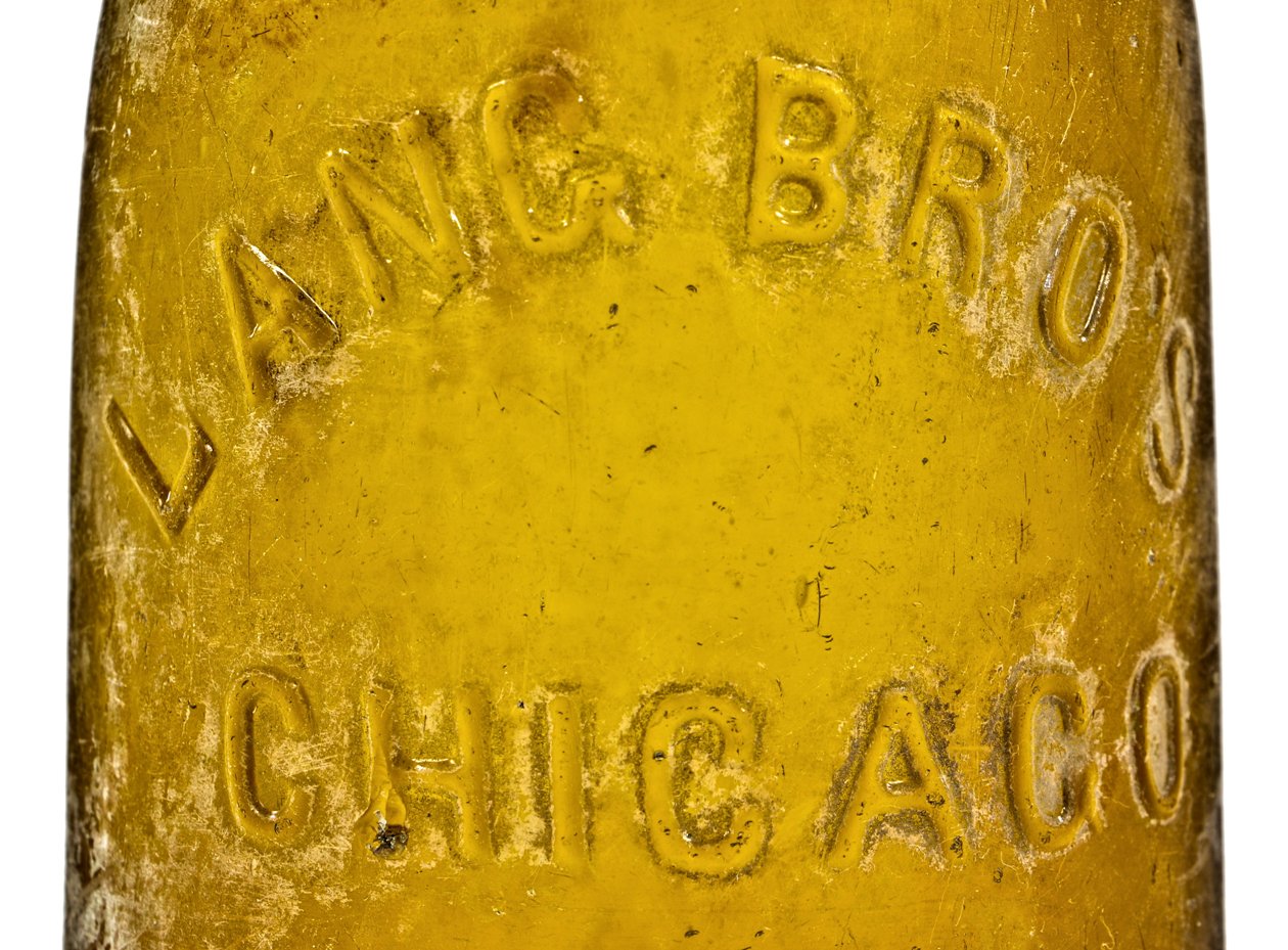 exceptionally rare antique american mid-nineteenth century privy dug vibrant yellow colored champagne style beer bottle with applied ring fabricated for the chicago bottlers the lang brothers.