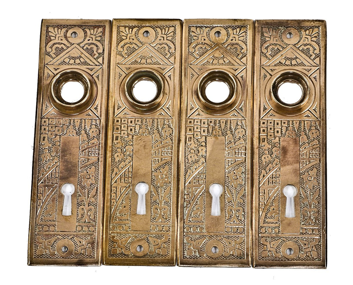 four original and intact antique american ornamental wrought brass "ceylon" pattern interior residential doorknob backplates or escutcheons with a mostly uniform surface finish