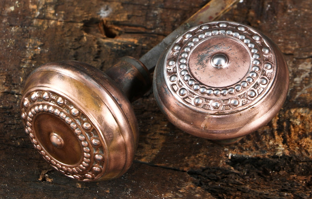 original early 20th century antique american stamped or wrought steel "como" pattern interior residential doorknobs with partially intact copper-plated finish