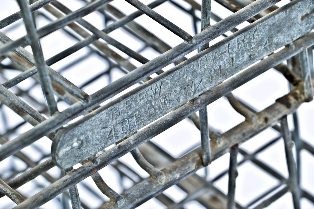 group of three matching american depression era reinforced industrial bent steel milk and/or dairy stackable storage crates with stamped steel identification tags