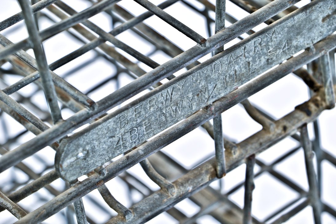 group of three matching american depression era reinforced industrial bent steel milk and/or dairy stackable storage crates with stamped steel identification tags