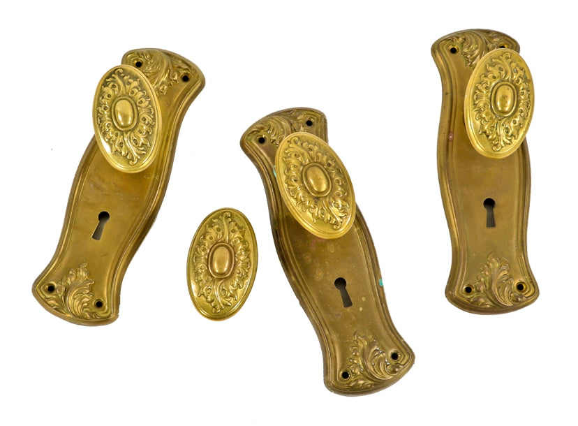 group of original matching early 20th century antique american stamped pressed brass interior residential backplates and oval-shaped doorknobs