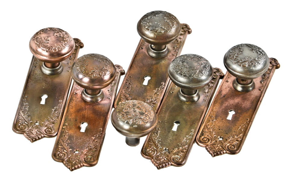 group of original early 20th century antique american interior residential copper-plated stamped steel "loriane" pattern banded rim doorknobs with matching backplates or escutcheons