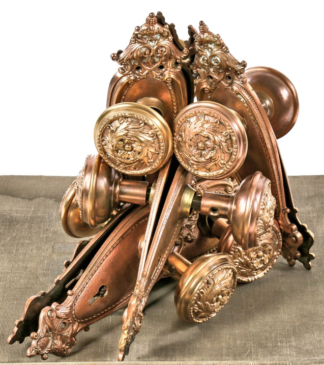 one of several matching brass-plated cast bronze interior residential late victorian era passage door locksets comprised of decorative doorknobs and uniquely shaped backplates