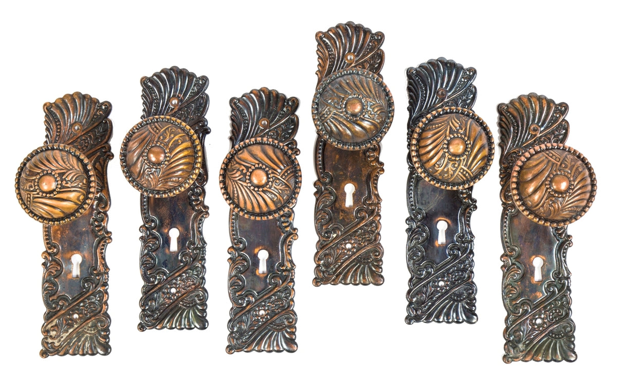 group of six matching early 20th century art nouveau style antique american salvaged chicago "roanoke" pattern doorknob and backplates with original finish largely intact