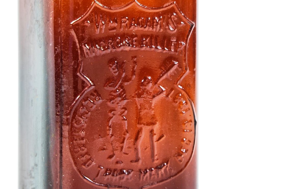 rare late 19th century antique american medical dark amber or brown glass "radam's microbe killer" embossed medicinal bottle with tooled plain lip