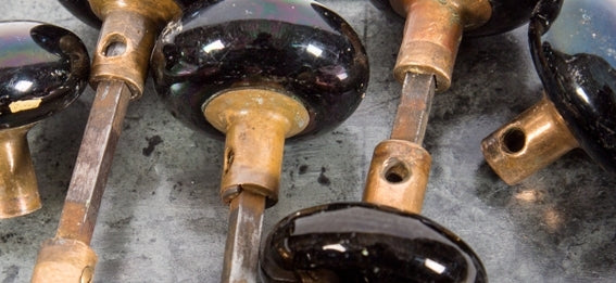 ten matching set of late 19th century original and intact "jet black" glazed ceramic interior residential doorknobs with nicely aged cast brass shanks