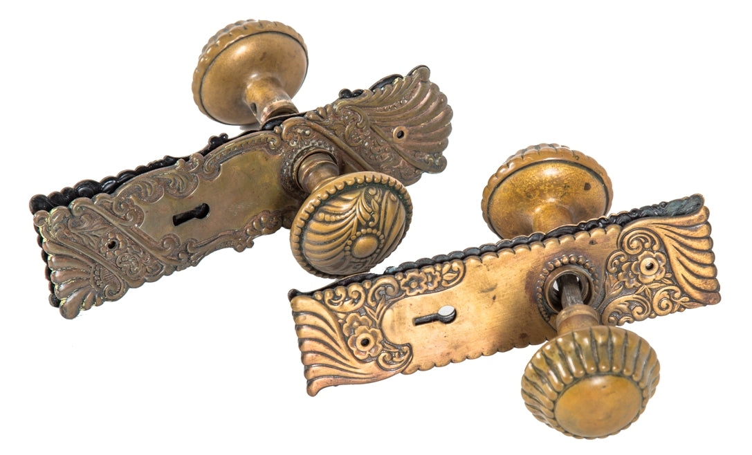 two nearly identical sets of original antique american art nouveau style wrought brass interior residential passage doorknob sets with matching backplates
