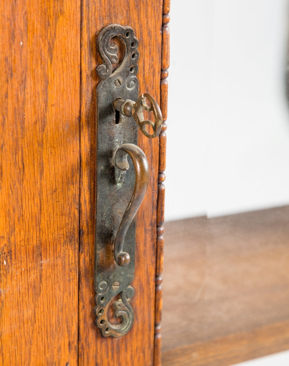all original late 19th century golden oak wood freestanding double-door bookshelf cabinet with beveled edge glass and original ornamental hardware with matching skeleton cabinet key