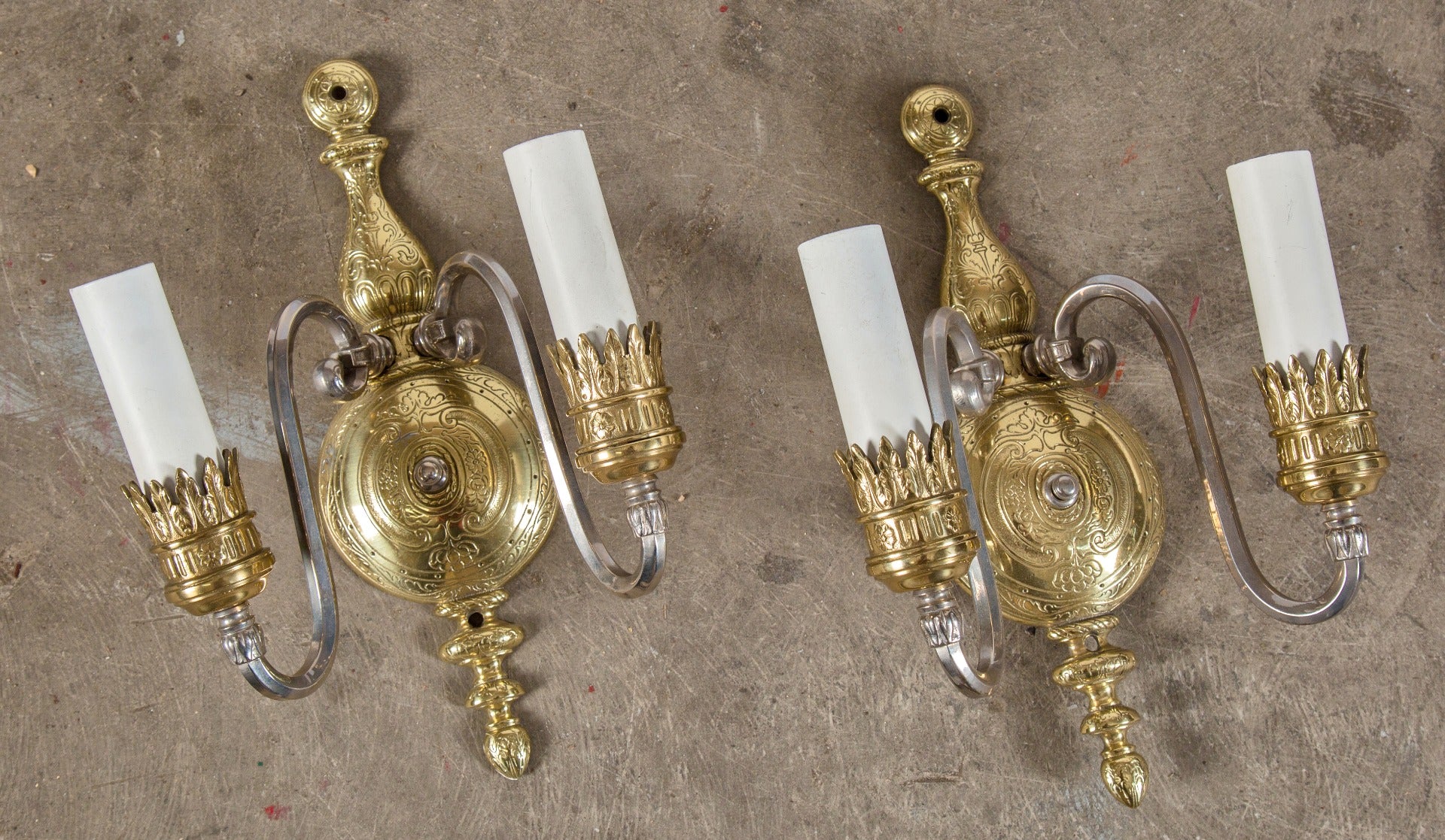refinished two-tone ornamental cast brass double-arm wall sconces with intricate incised design and white candle sleeves