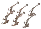 group of six matching original ornamental cast iron figural grotesque oversized parlor or hall tree hooks with traces of copper-plated finish