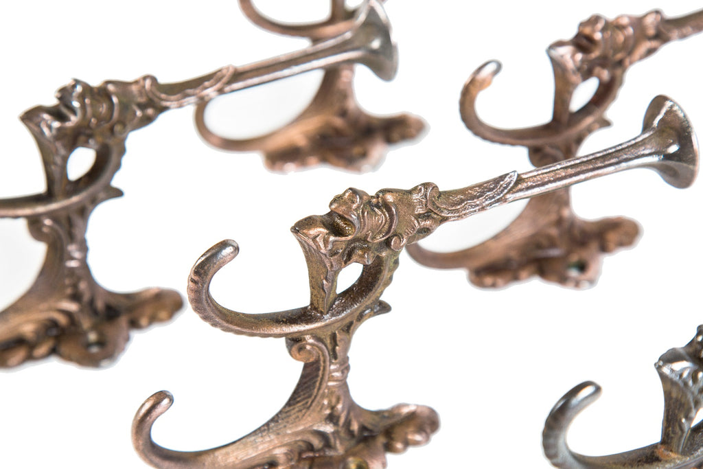 group of six matching original ornamental cast iron figural grotesque oversized parlor or hall tree hooks with traces of copper-plated finish