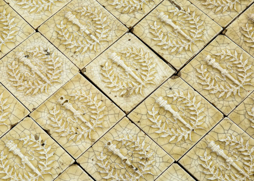original 19th century 3 x 3 inch yellow glazed deeply embossed majolica tiles with torches and laurel wreaths