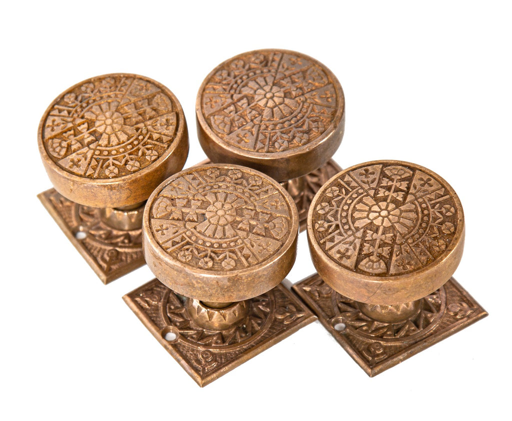 group of four hard to find 19th century ornamental cast brass eastlake style doorknobs with matching squarer-shaped rosettes