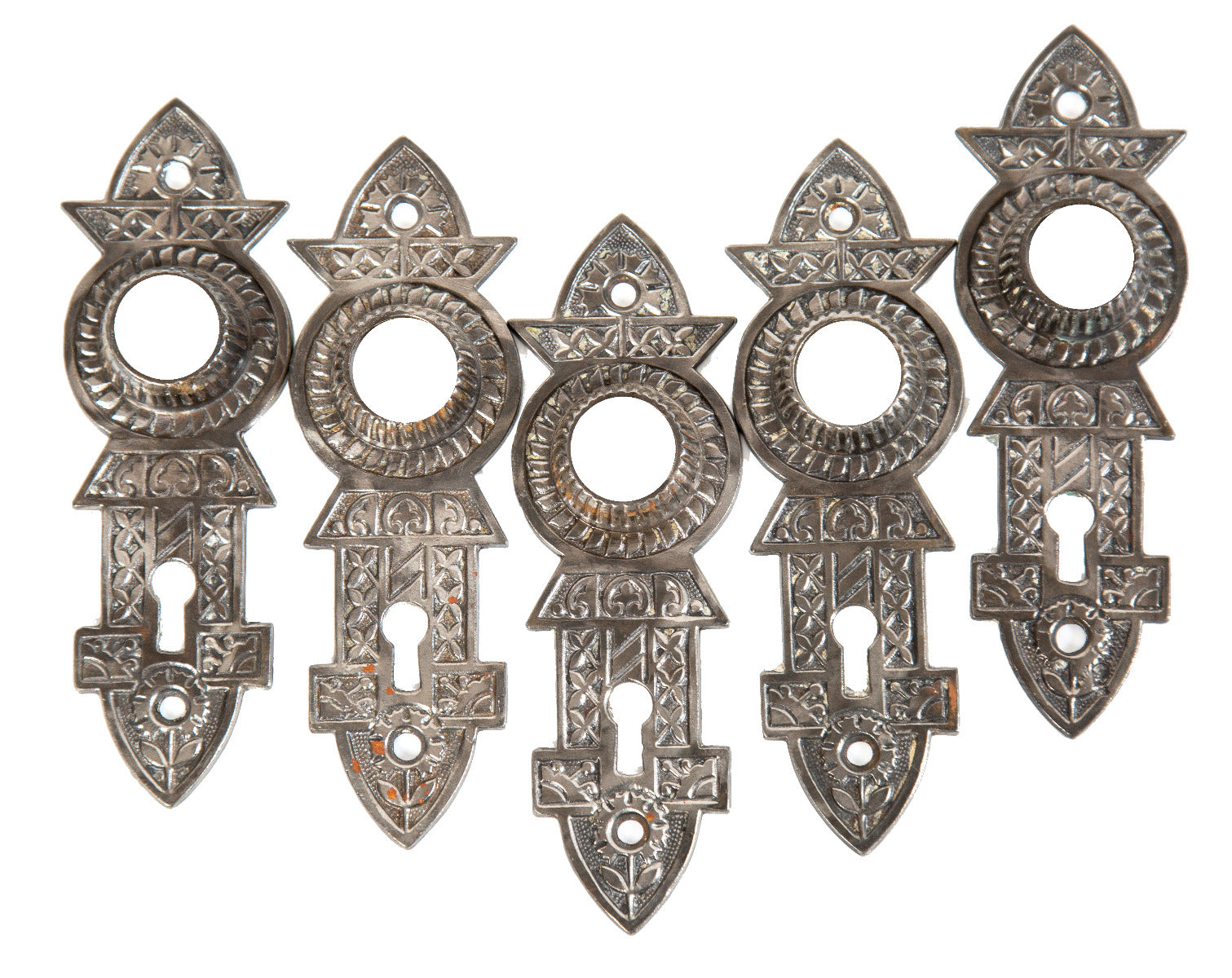 group of five matching original brushed ornamental cast iron chicago-niles "screwless" spindle doorknob backplates