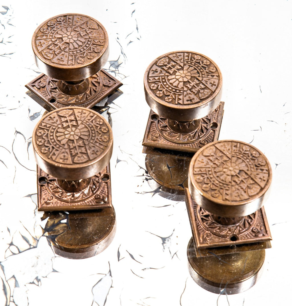 group of highly desirable antique american eastlake style ornamental cast bronze penn drum-shaped doorknobs and matching rosettes