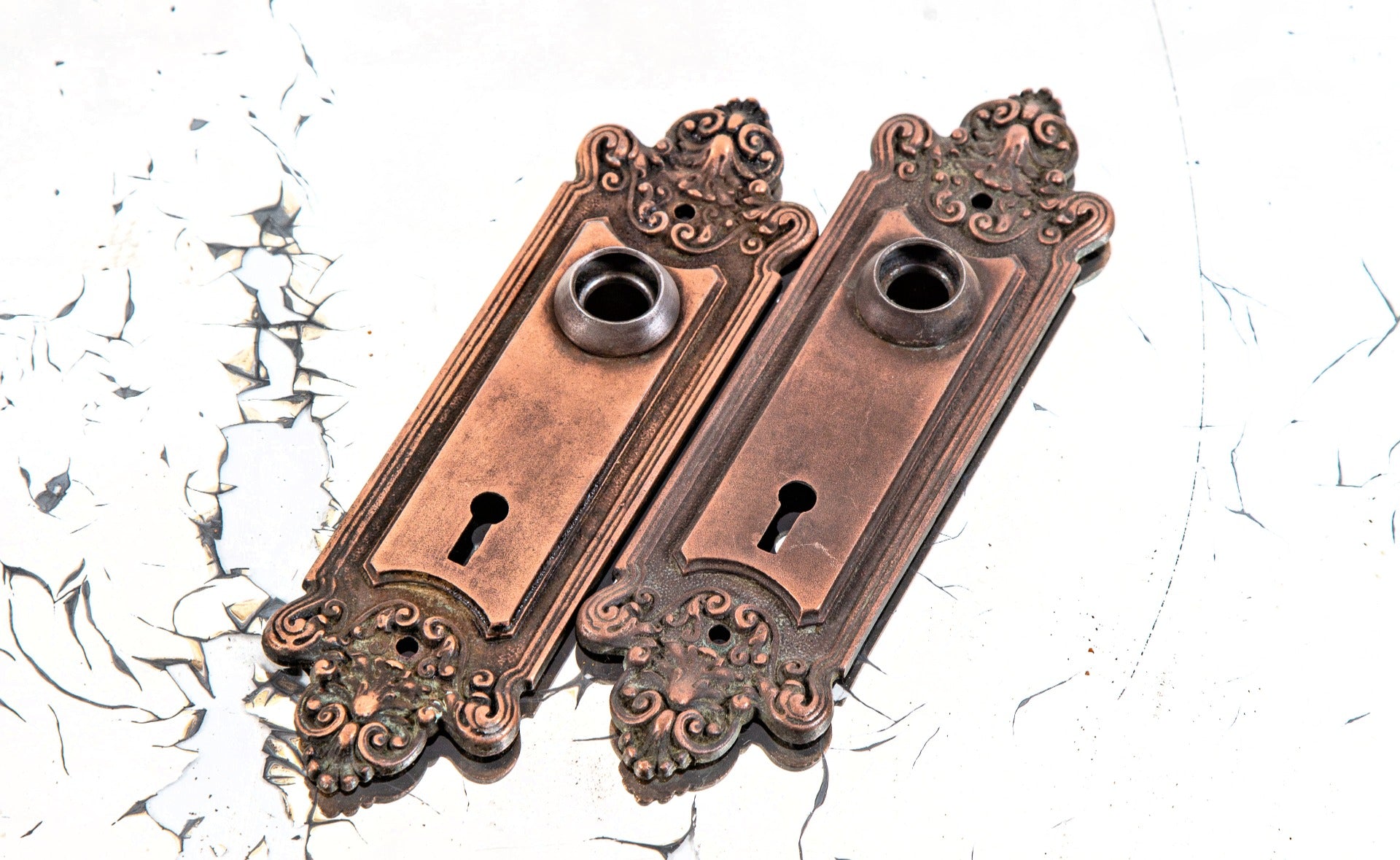 matching set of original early 20th century copper-plated ornamental cast iron "truro" pattern doorknob backplates