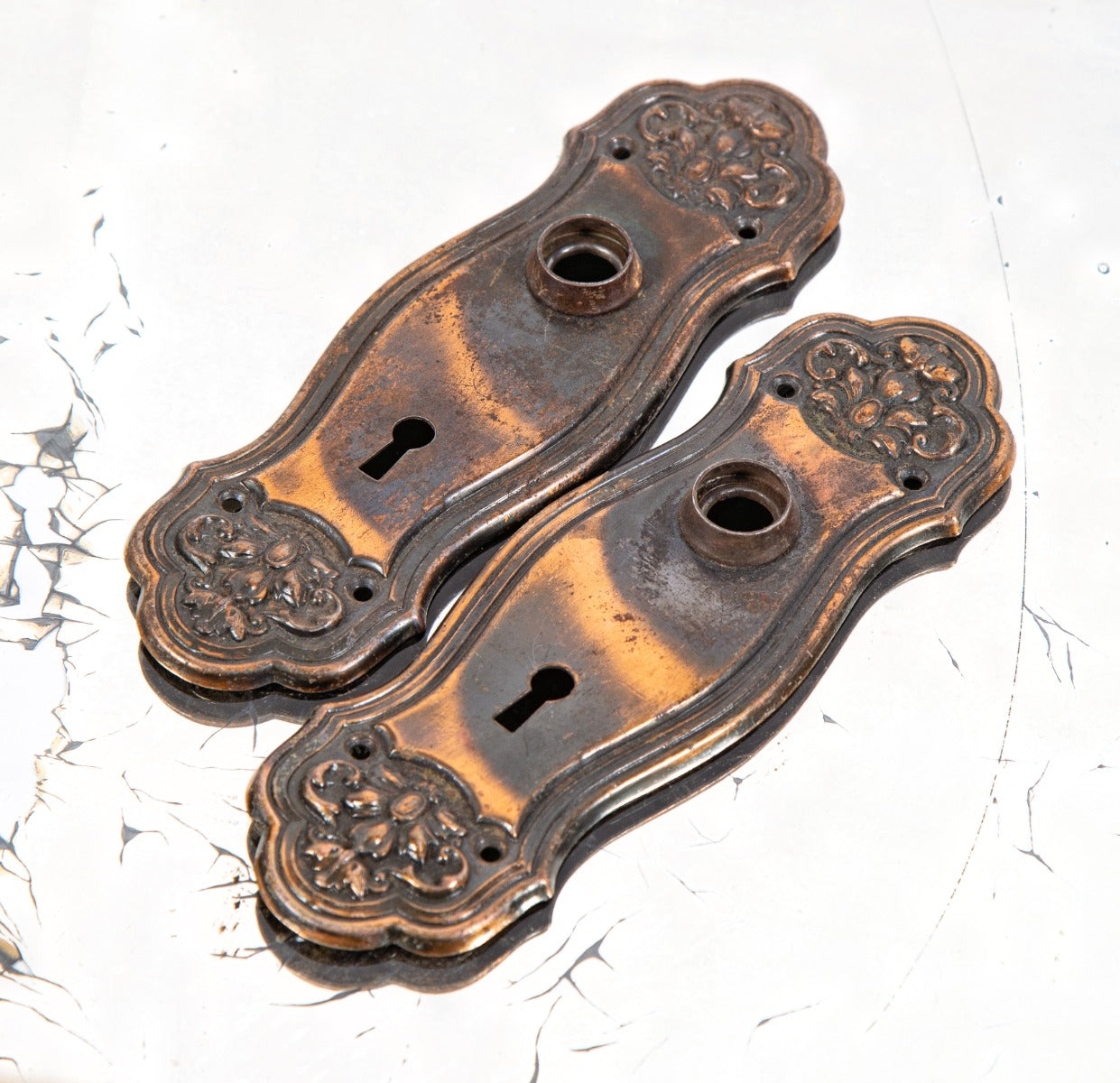 pair of early 20th century stamped ornamental steel salvaged Chicago doorknob backplates with original oxidized copper finish