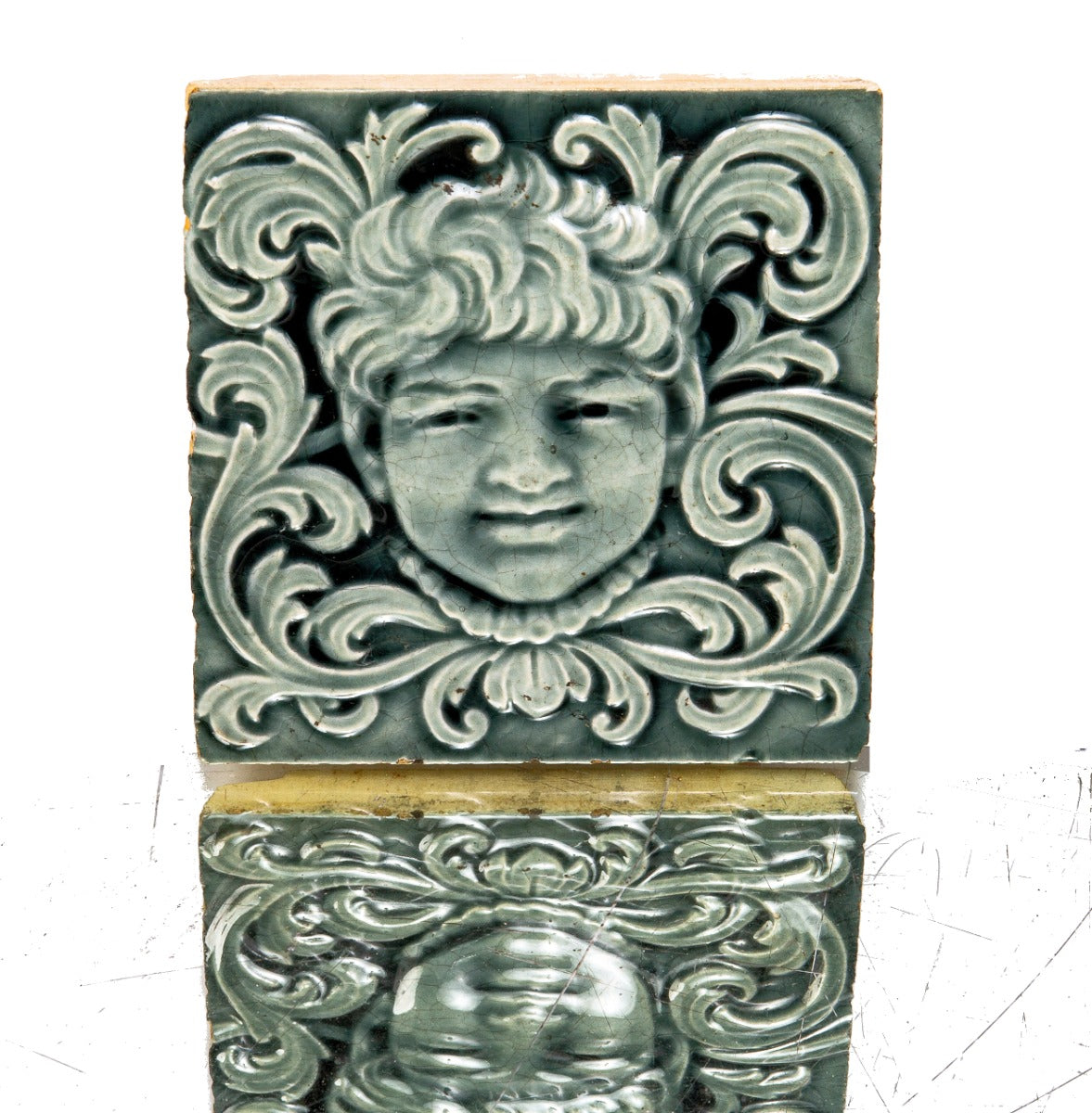 late 19th century original 6 x 6 inch majolica-glazed trent figural fireplace tile featuring centrally located face surrounded by foliage
